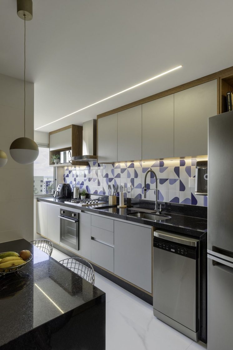 Cozinha em cores neutras, armários cinzas e rodabanca com revestimentos com desenhos azuis inspirados nos azulejos de Athos Bulcão