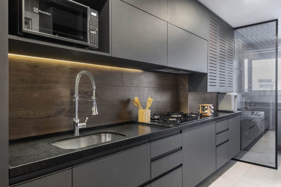 Cozinha com paleta de cores escuras, armários grafite e rodabanca com revestimento amadeirado
