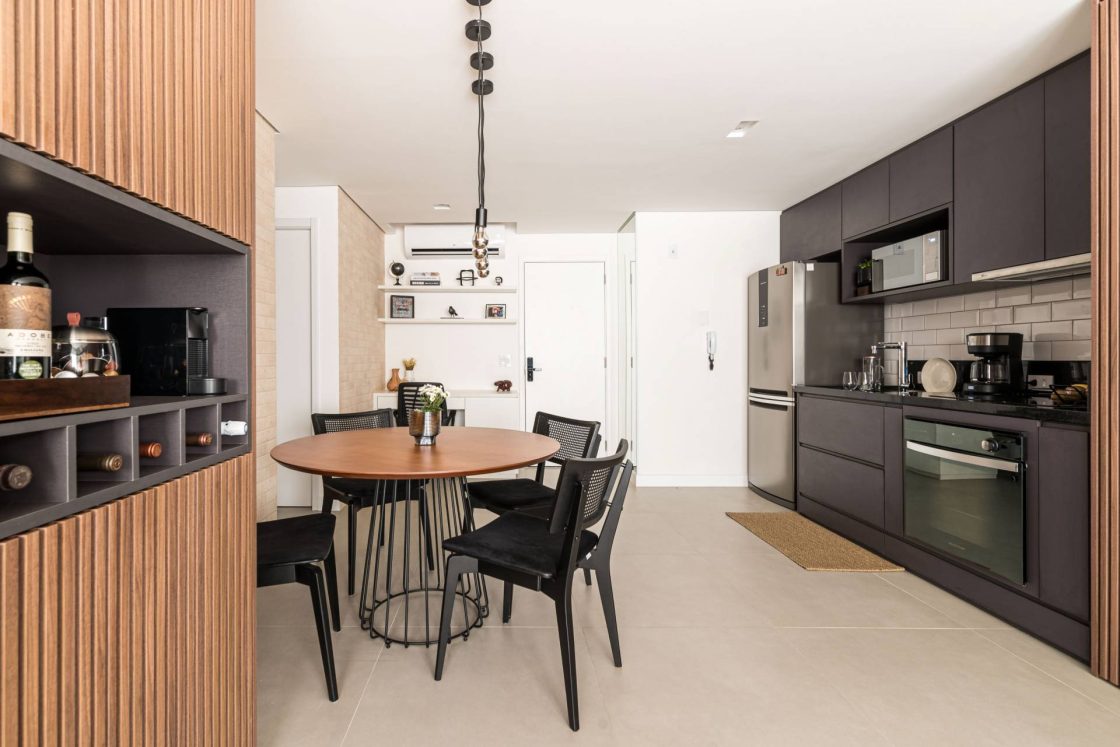 Ambiente integrado de sala de jantar e cozinha com destaque para o branco, preto e madeira