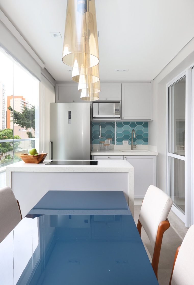 Cozinha compacta em tons de branco e azul em sacada de apartamento