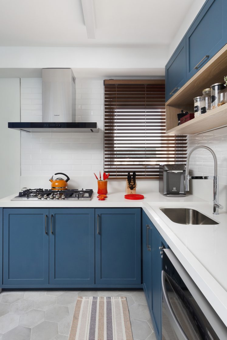 Cozinha com paredes claras, revestimento com efeito cimento queimado, prateleiras em madeira e armários em azul