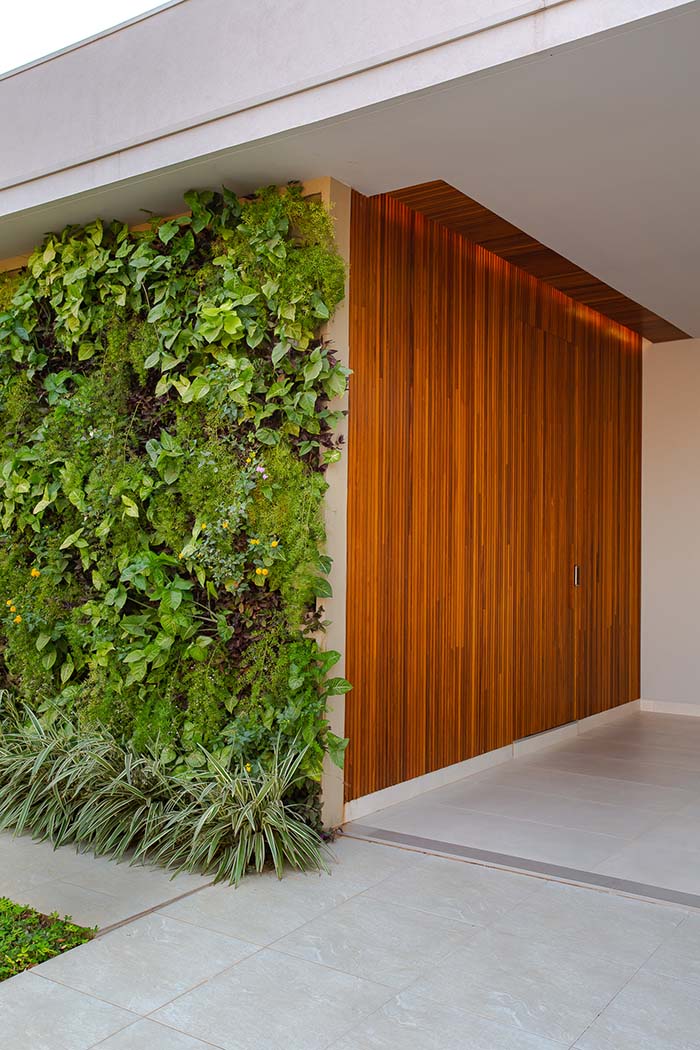 Muro verde com porta de madeira e piso de porcelanato
