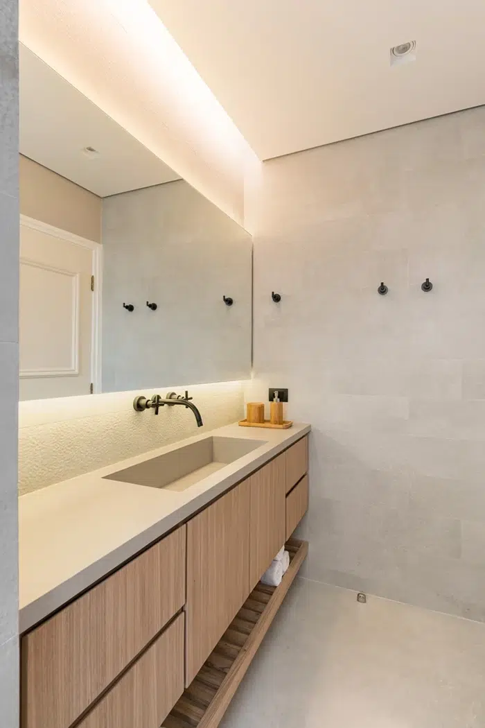 Banheiro moderno com iluminação aconchegante mostrando bancada, pia e torneira