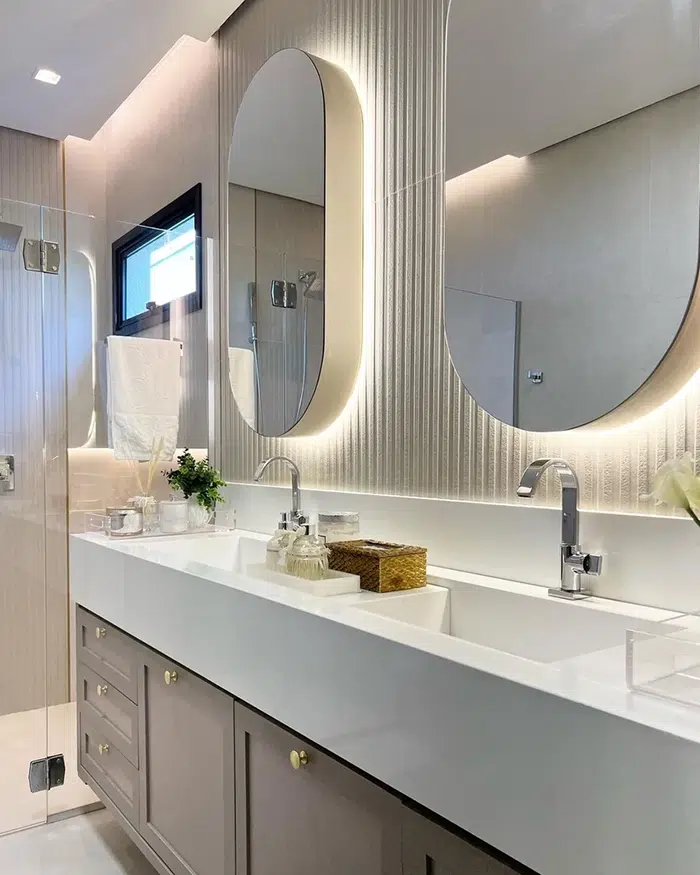 Banheiro moderno com bancada de pia, torneira e espelhos ovais