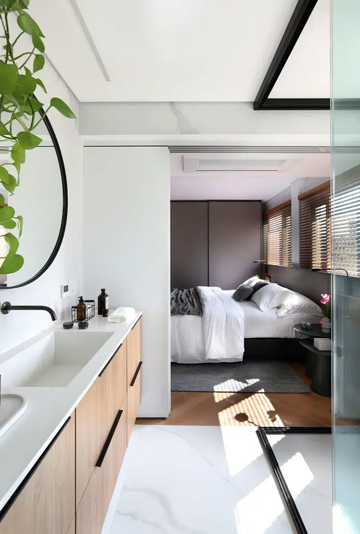 Banheiro moderno com bancada com painel de automação e piso aquecido mostrando pia, torneira, espelho e quarto com cama