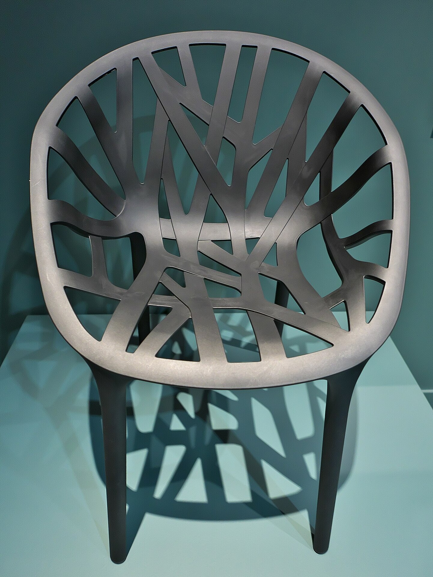 Cadeira em plástico com encosto arredondado, que lembra as ramificações de uma planta