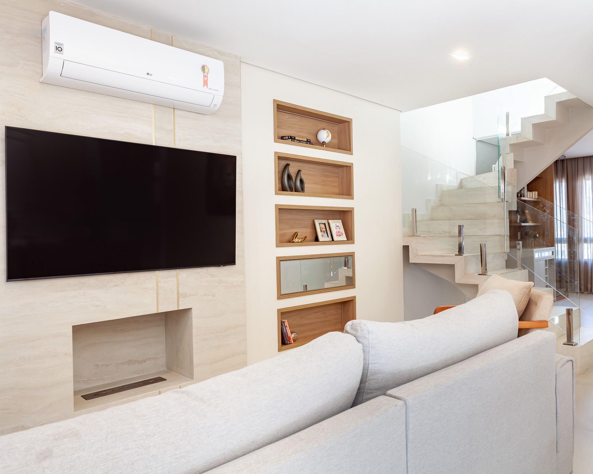 Sala de TV clara com painel e lareira em porcelanato marmorizado