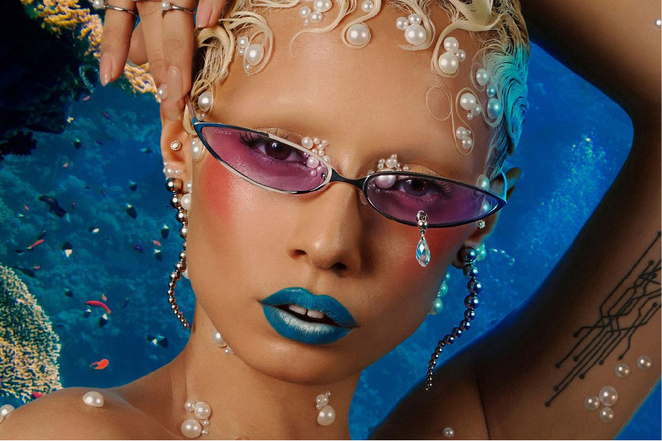 Mulher com cabelos curtos cheio de pérolas, óculos com lentes roxas e batom azul