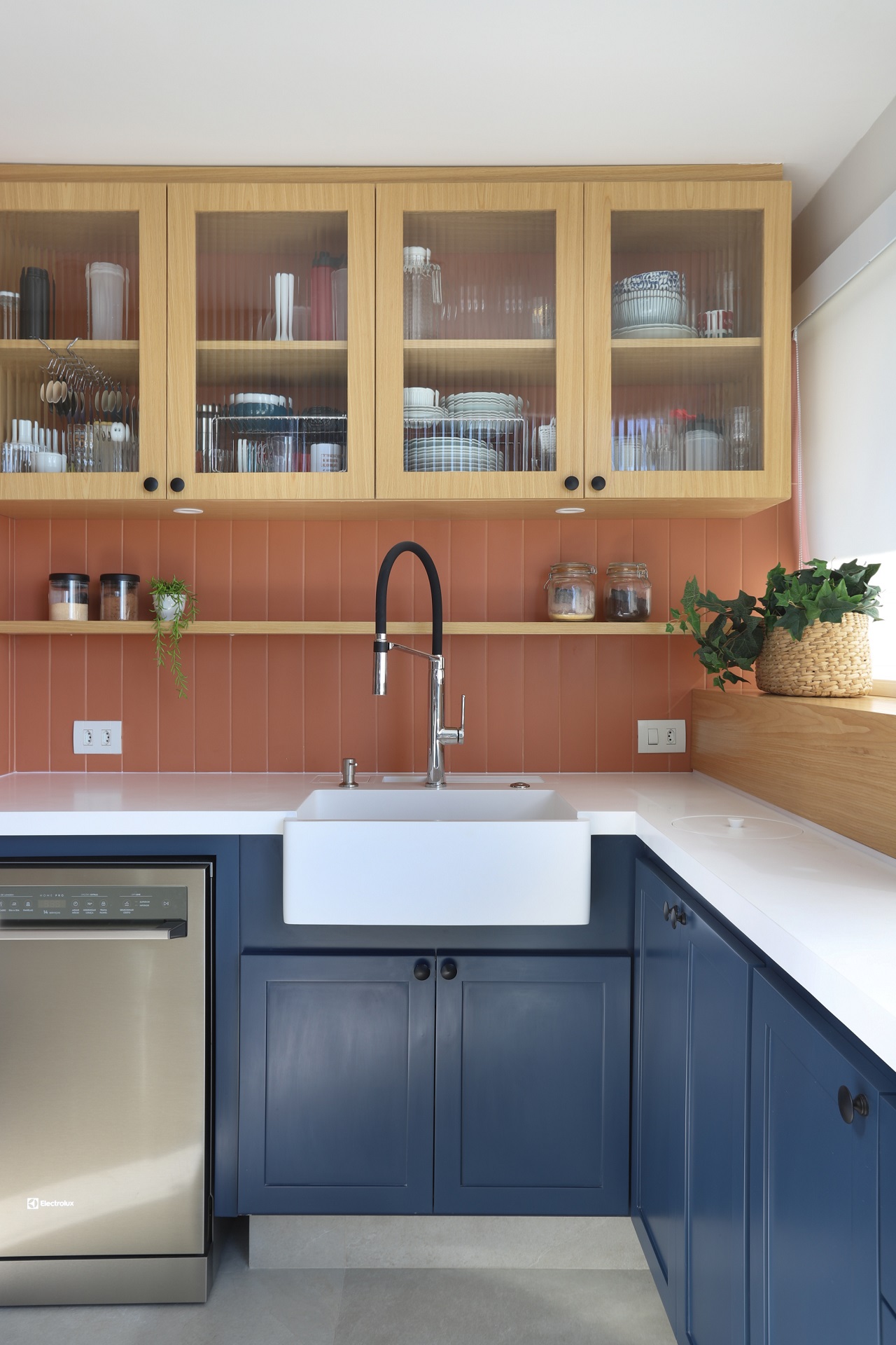 Cozinha com armários em madeira e azul; bancada branca; e backsplash laranja