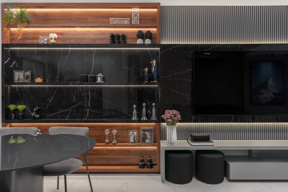 Living com painel de televisão ripado e detalhe centralizado com mármore preto em porcelanato