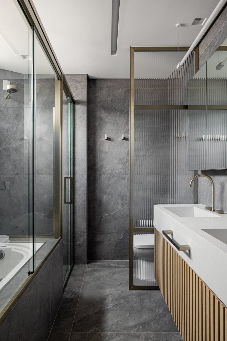 Banheiro com banheira e revestimento de porcelanato que reproduz mármore cinza