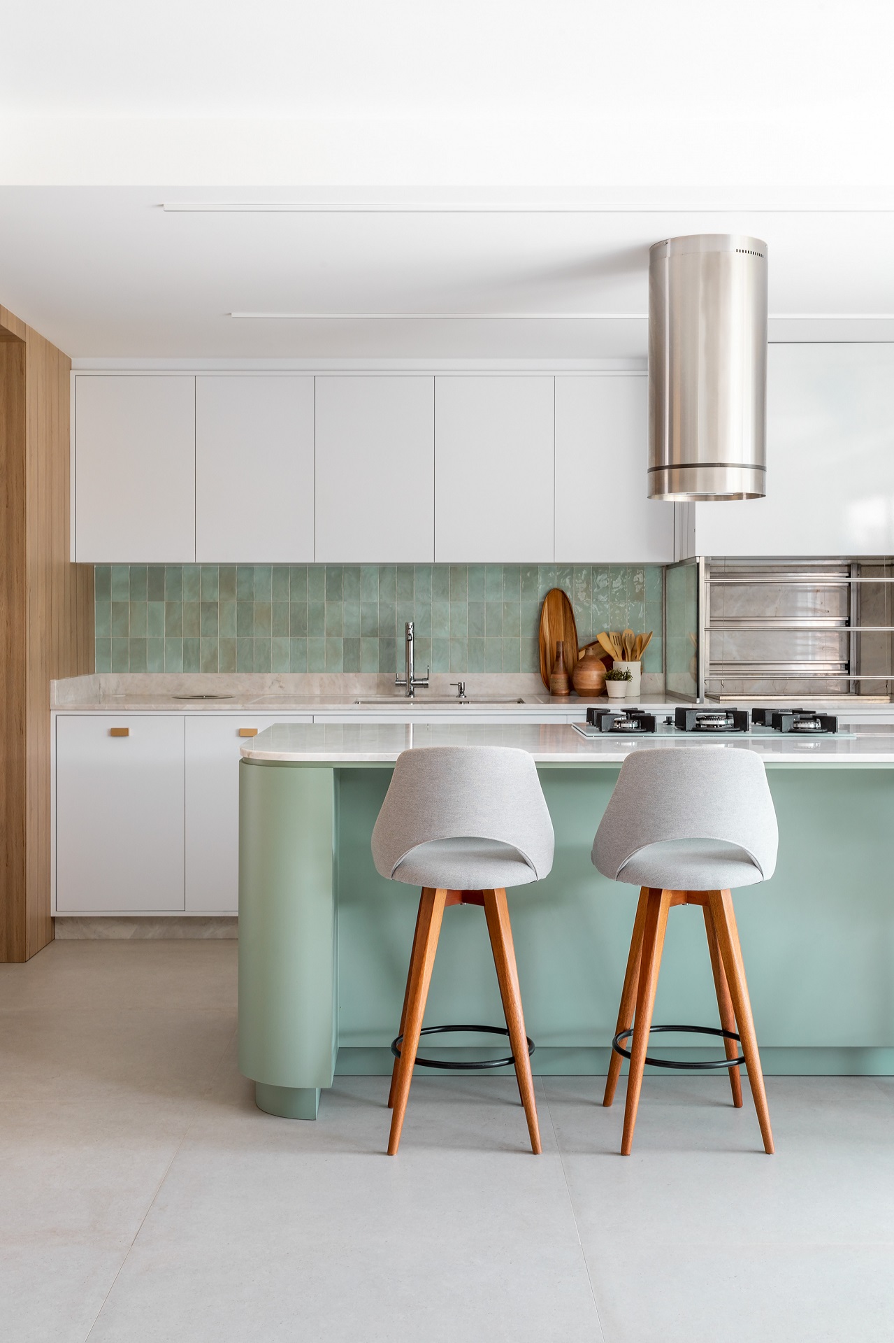Cozinha integrada em tons de branco e verde-claro, além de detalhes em madeira