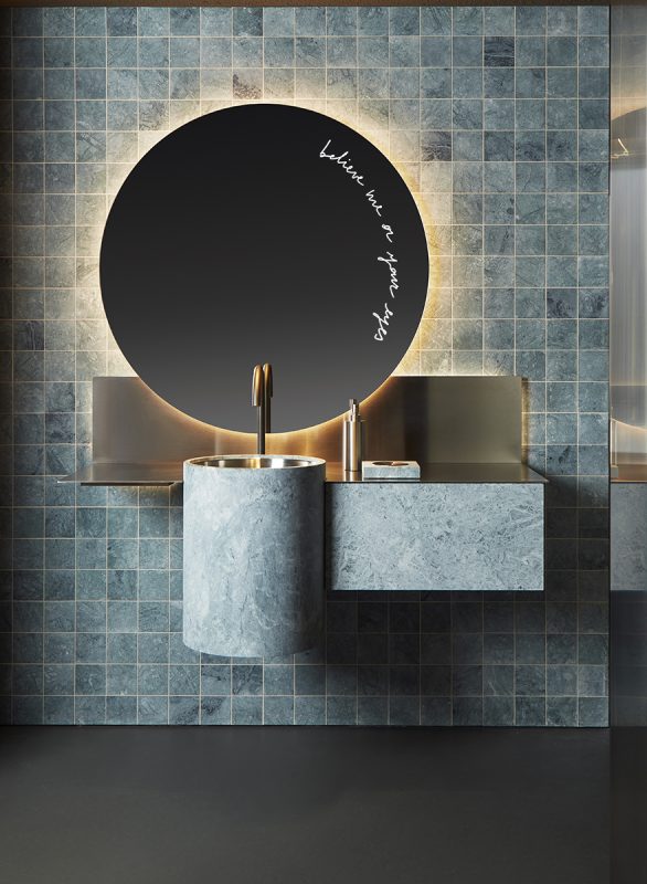 Bancada de banheiro com cuba e espelho redondos. Tanto a bancada quanto o revestimento na parede atrás são azuis