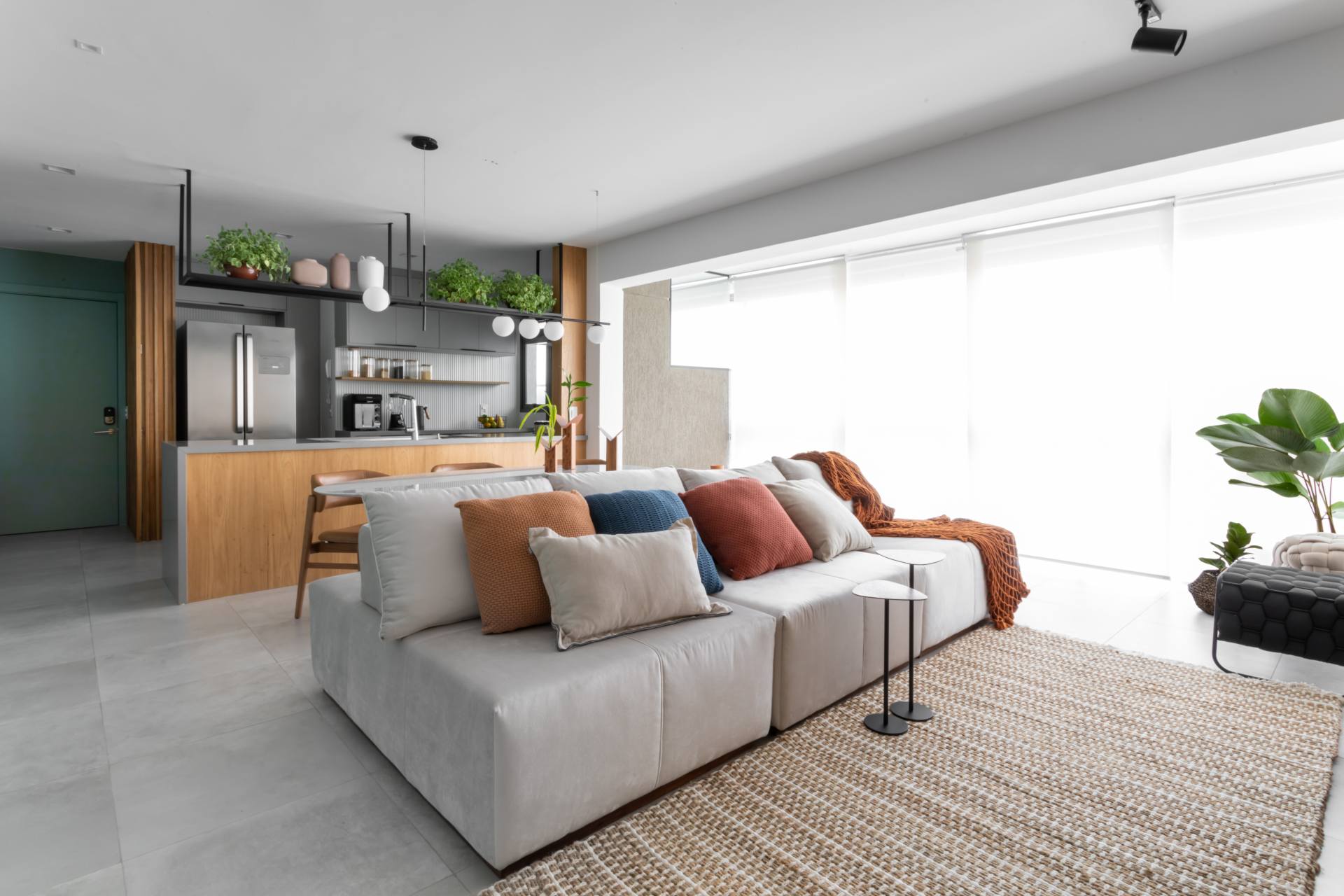 Sala de estar integrada à cozinha e à varanda, com base neutra e detalhes coloridos