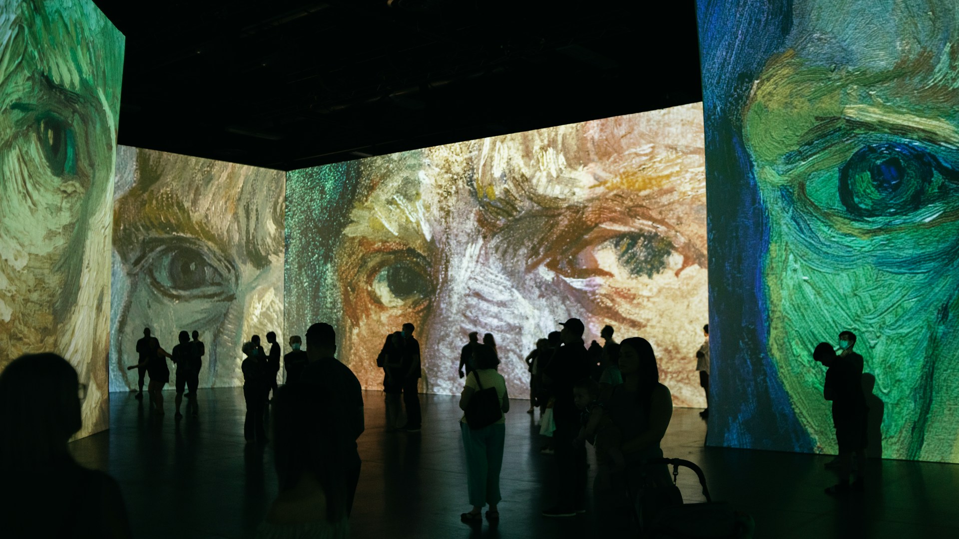Sala escura com projeções mapeadas de Van Gogh, exposição de arte com pessoas visitando