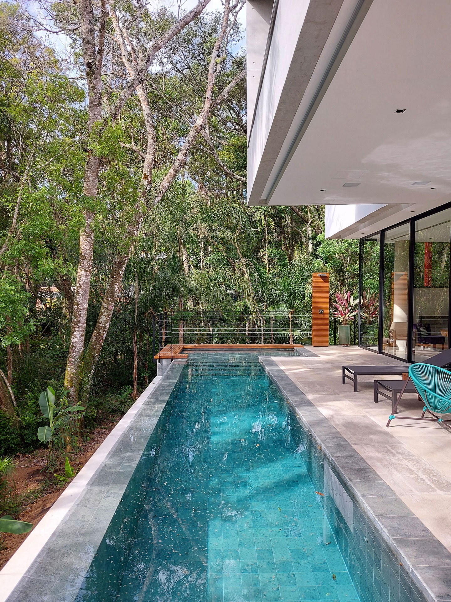 Piscina na área externa de casa moderna. Há muita natureza preservada ao redor