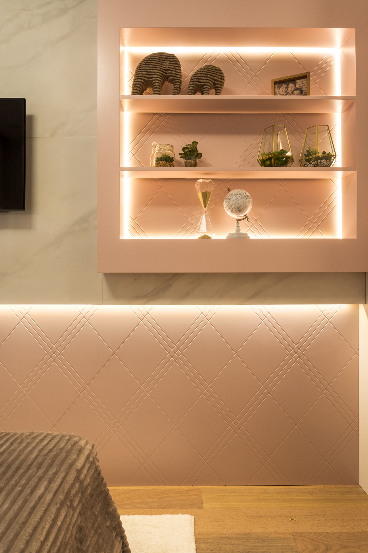 Prateleiras com luz de LED, objetos de decoração e parede em tom de rosa-claro e branco