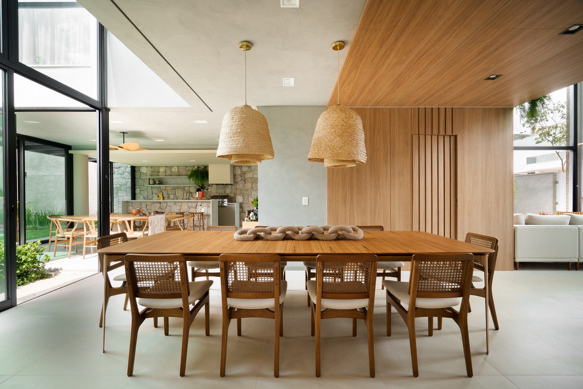 Sala de jantar com mesa ampla. No ambiente há um painel de madeira