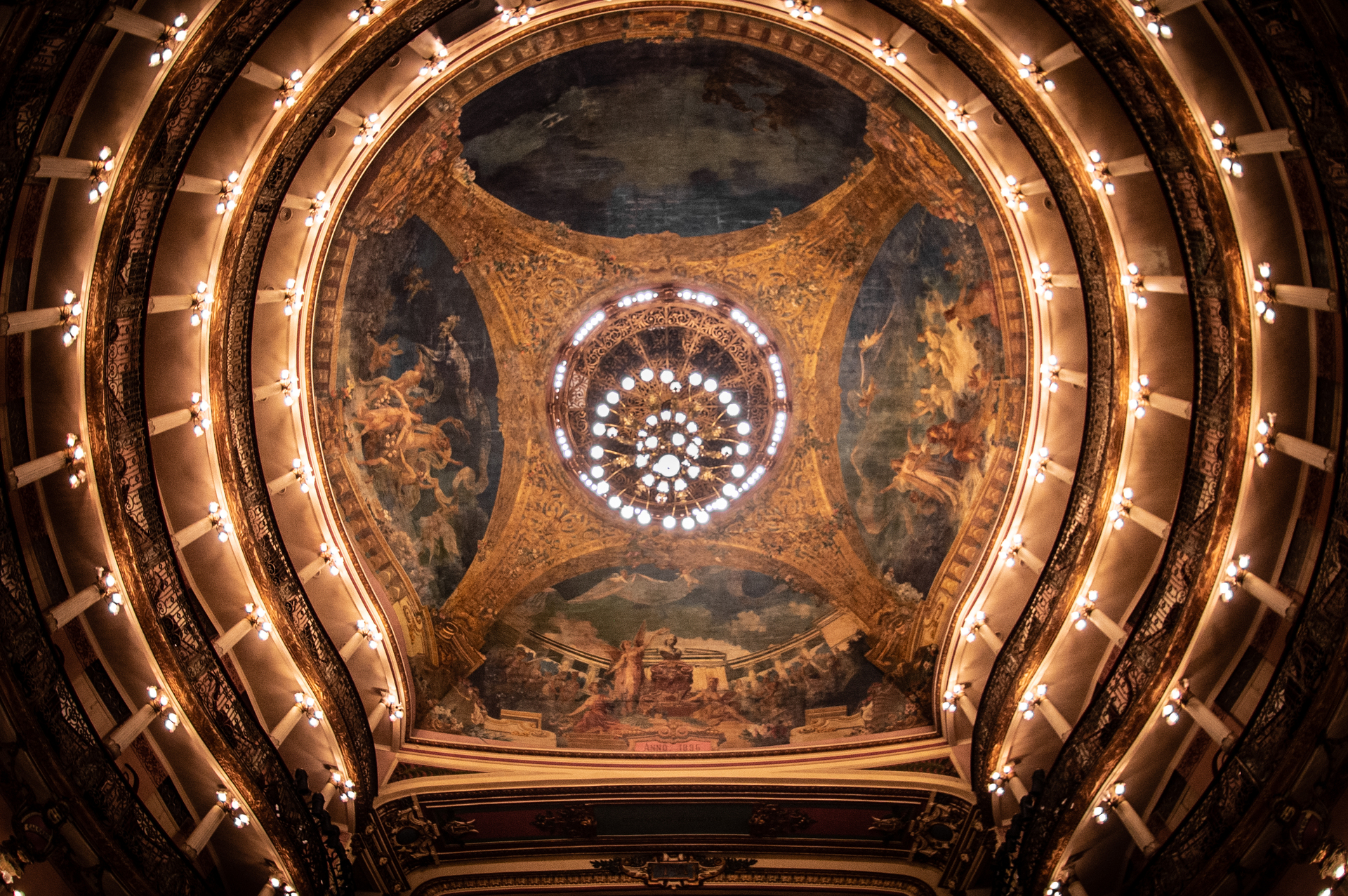 Teto do Teatro Amazonas, em formato côncavo, com um lustre com adornos e quatro pinturas no teto