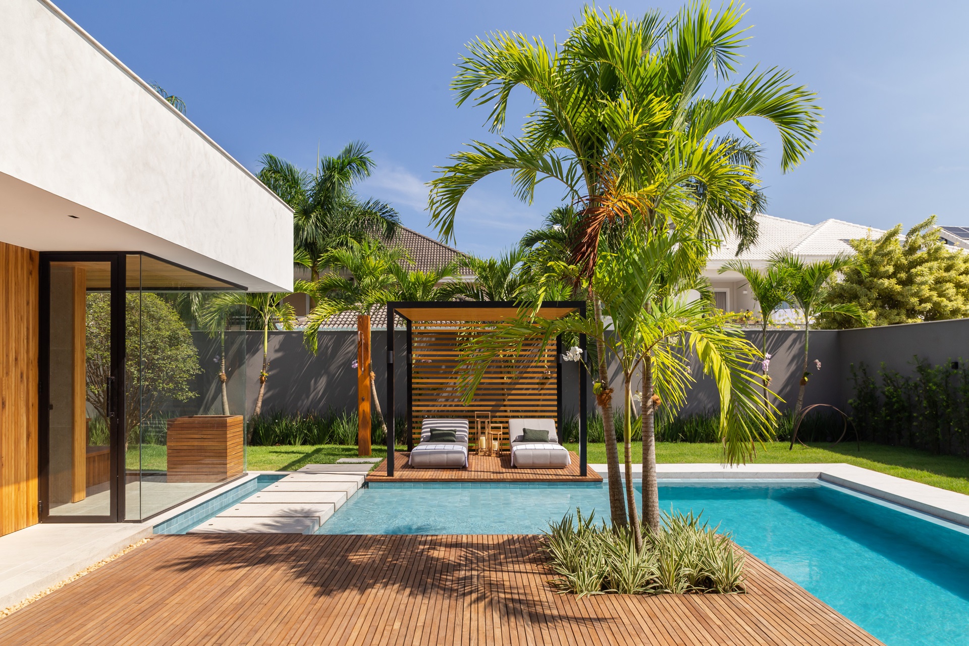 Área externa com piscina, deck, espreguiçadeiras e paisagismo