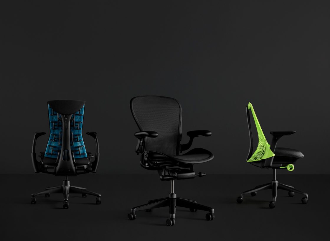 Fotografia still de três modelos de cadeiras gamers da Herman Miller sobre um fundo preto: uma Emody Gaming azul e preta, uma Aeron Gaming preta, e uma Sayl Gaming verde neon e preta, nesta ordem.