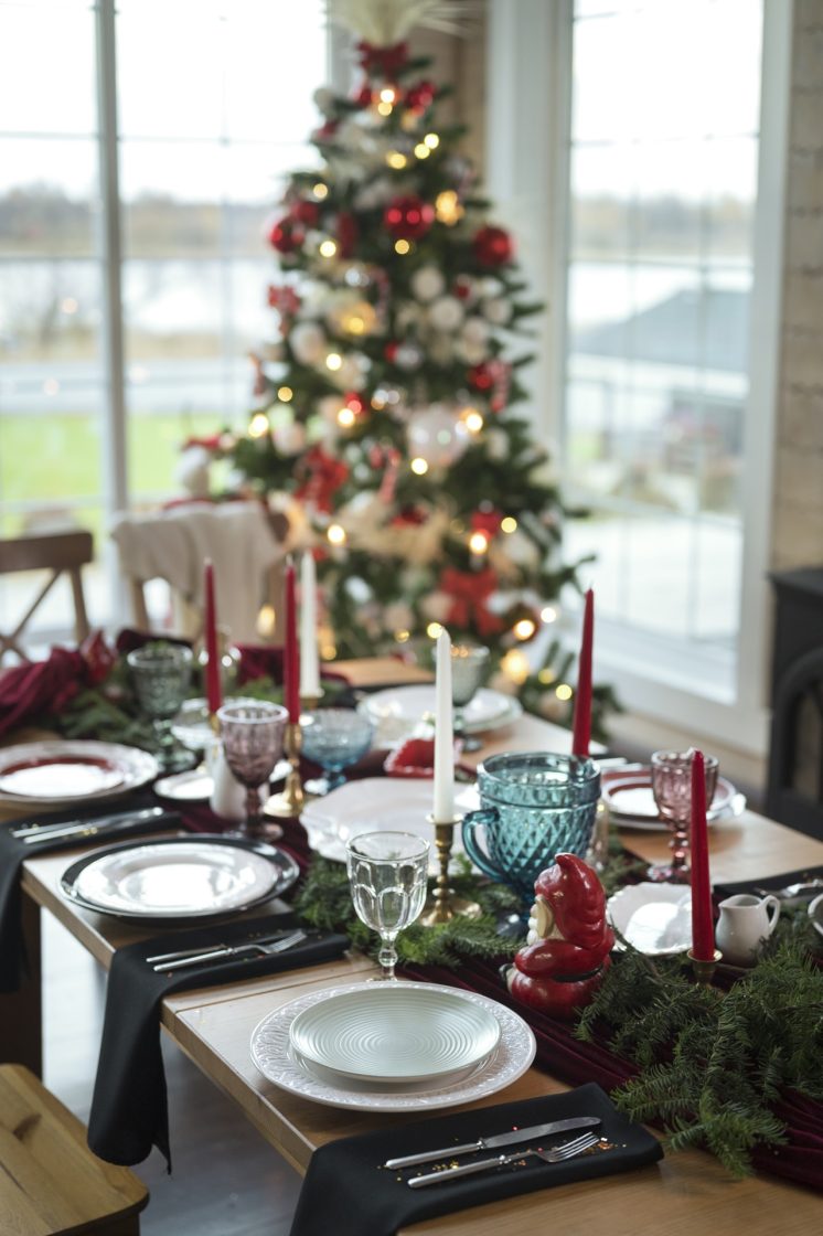 Mesa posta de Natal em foco, com árvore de Natal desfocada ao fundo