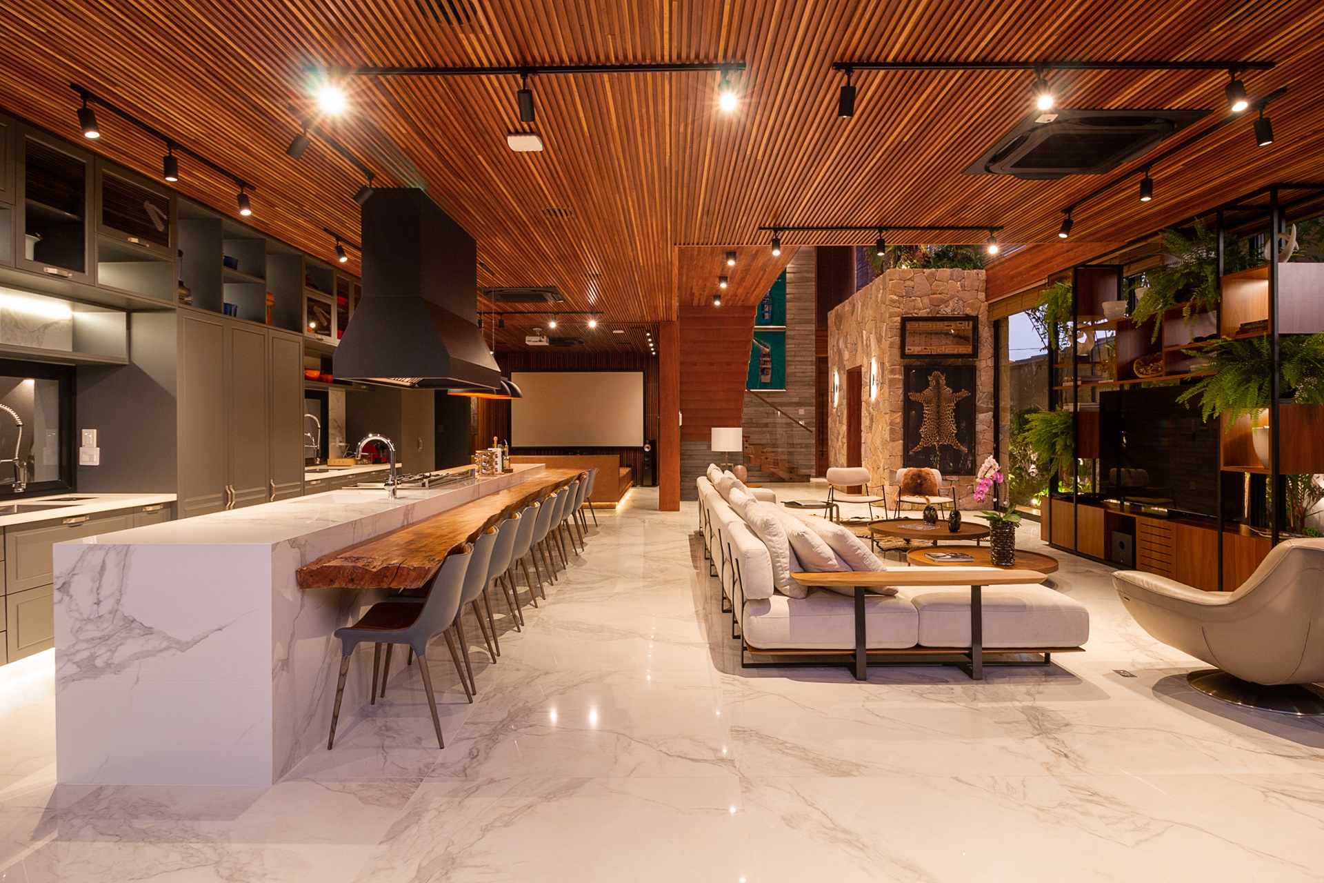 Ambiente amplo, com cozinha e sala de TV integradas. Destaque para o piso marmorizado e o forro de madeira