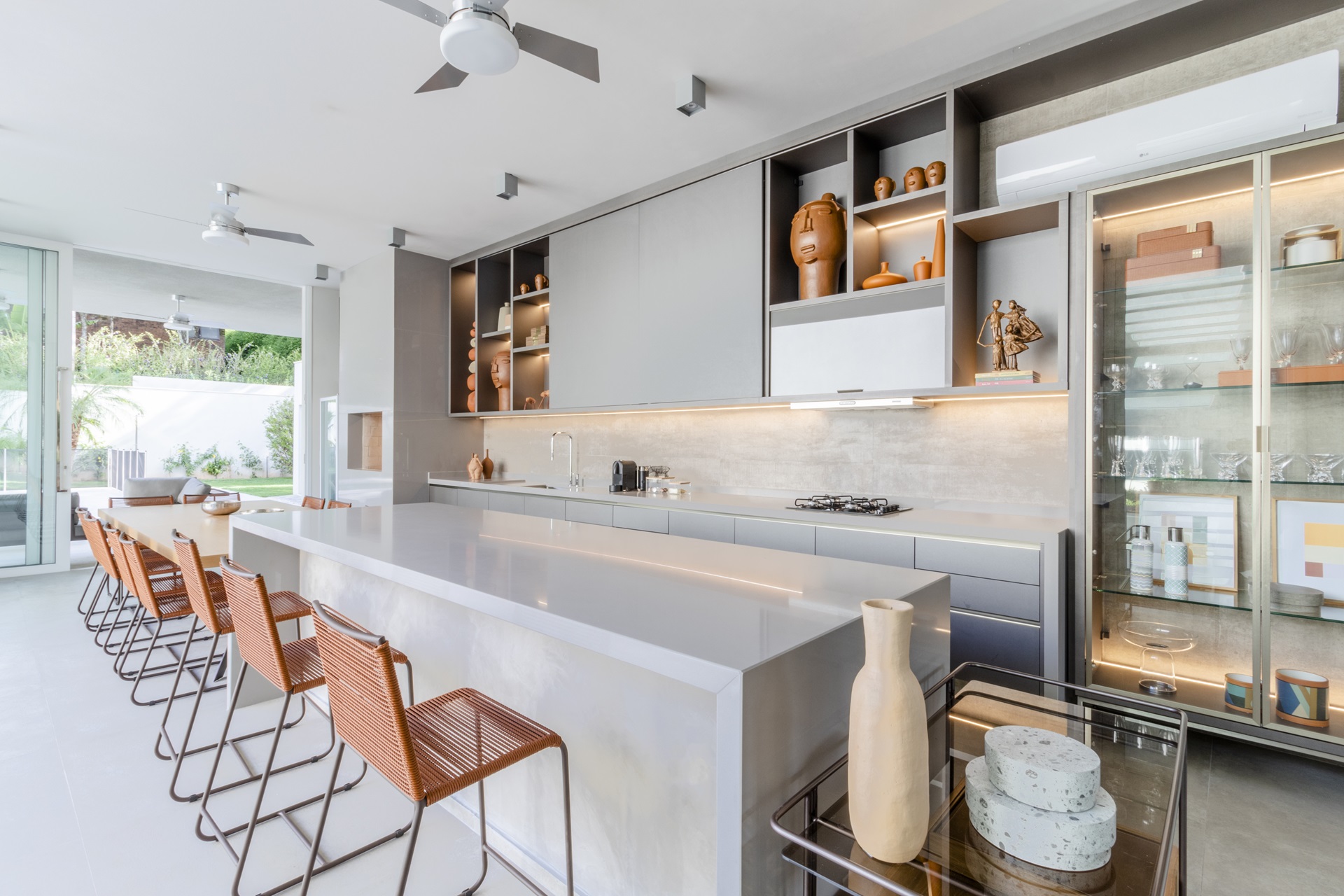 Cozinha em tons claros com ilha e peças de decoração como vasos e esculturas