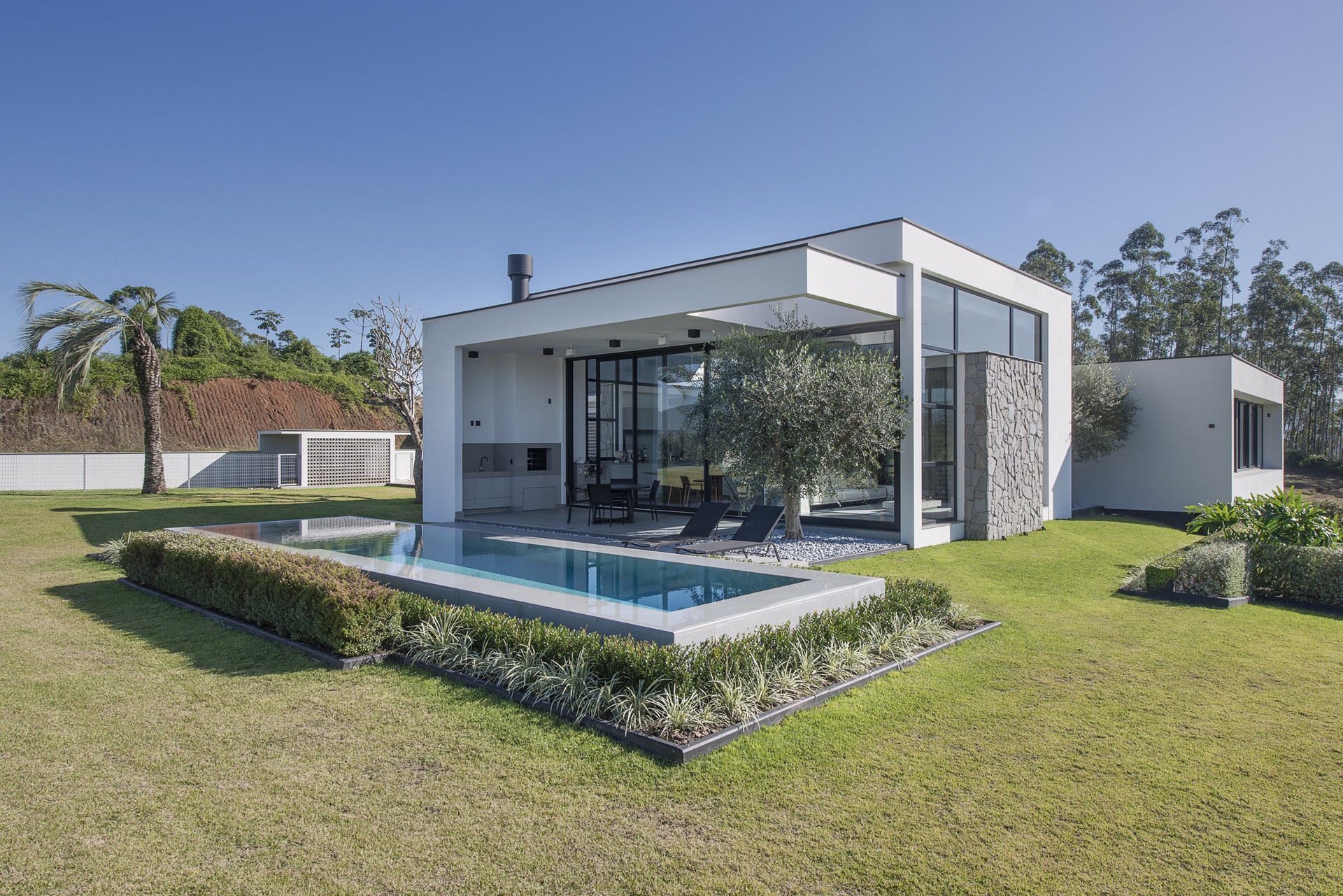 Área externa de casa em estilo contemporâneo com piscina retangular em alvenaria