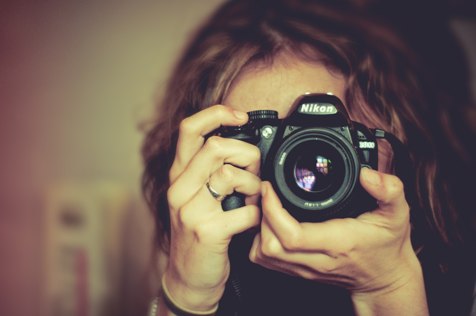 Mulher com uma câmera fotográfica da Nikon em frente ao seu rosto
