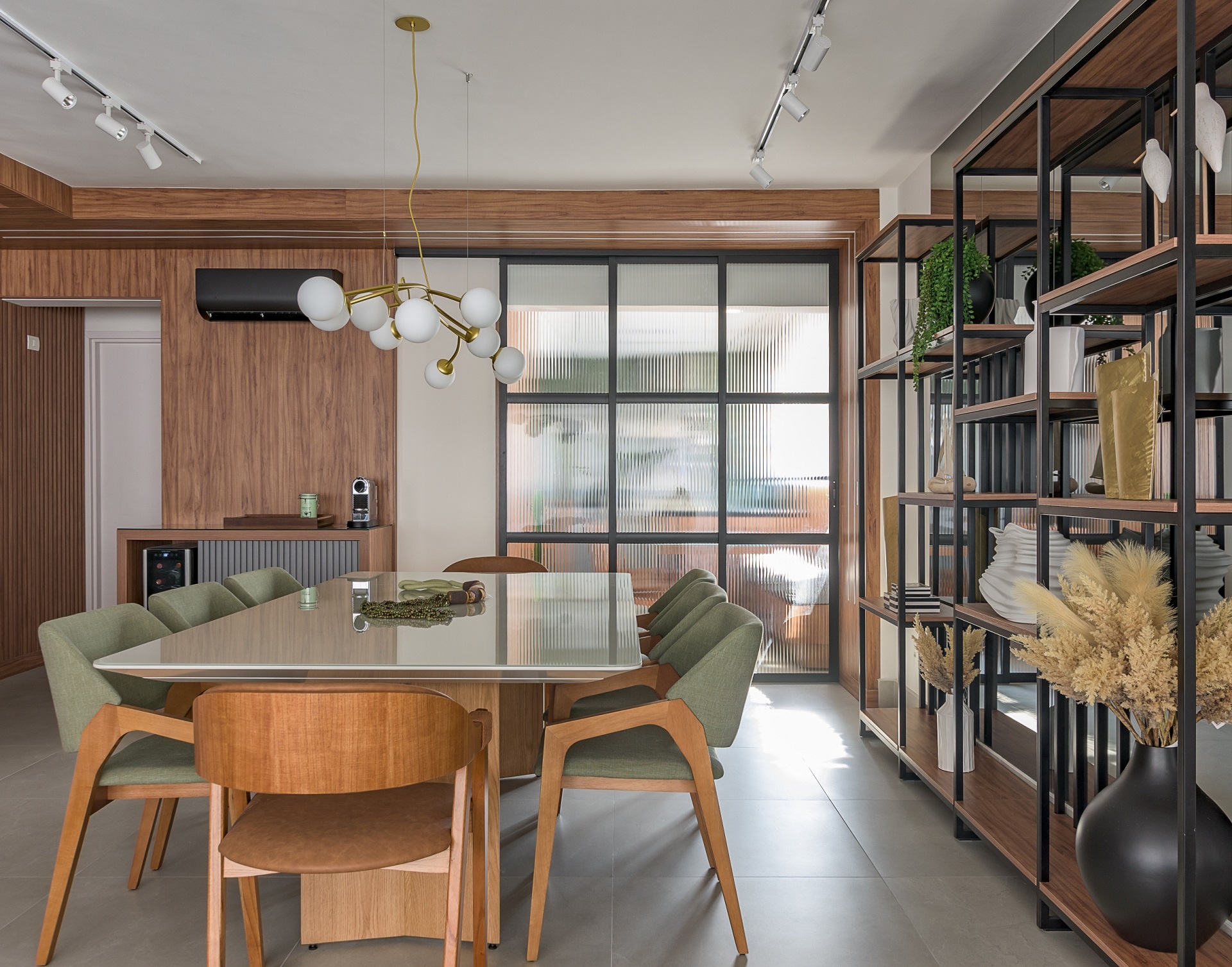 Sala de jantar com mesa ampla, buffet, prateleira, painel de madeira e porta de correr com vidro canelado