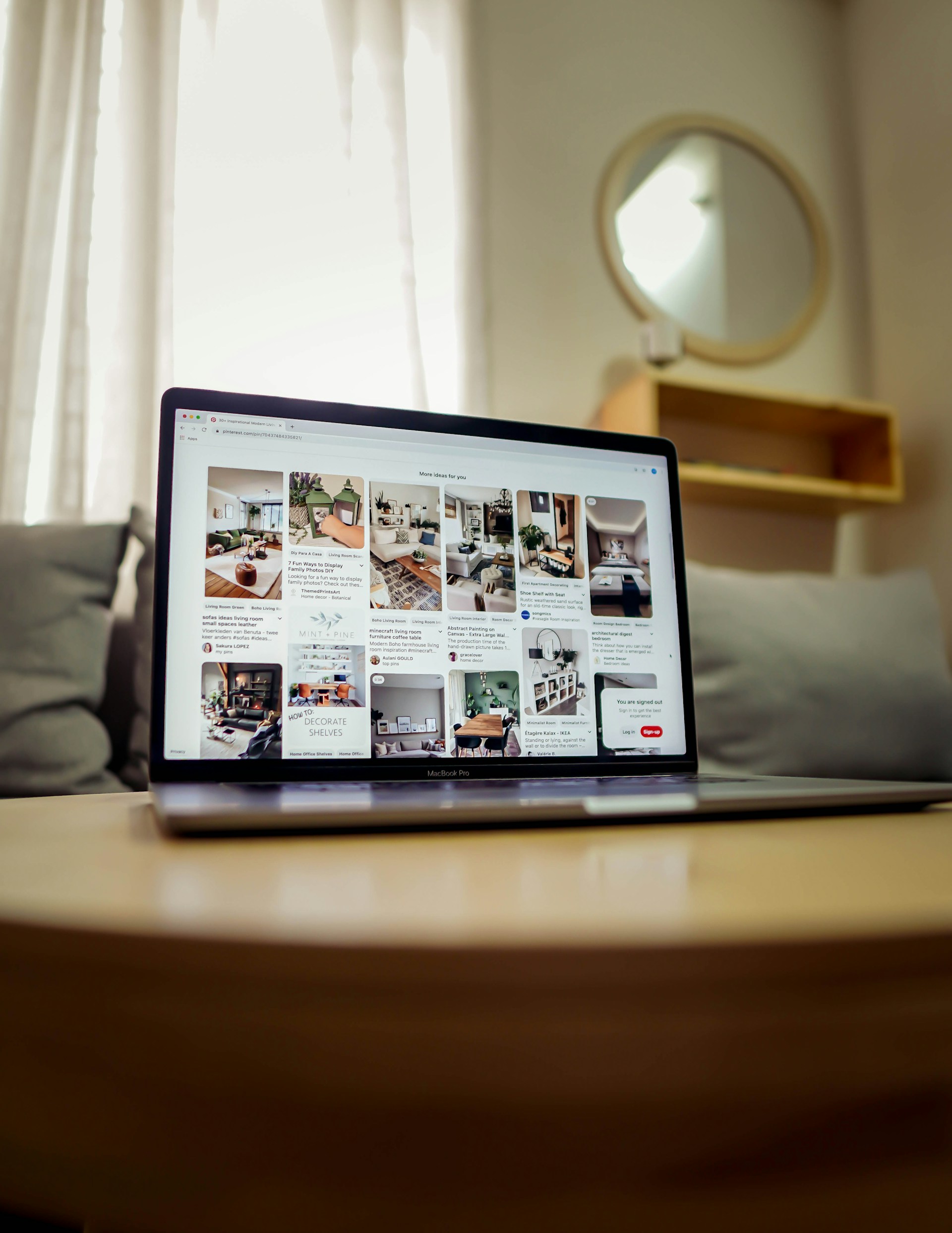 Notebook sobre mesa de centro em sala. Na tela aparece o feed do Pinterest