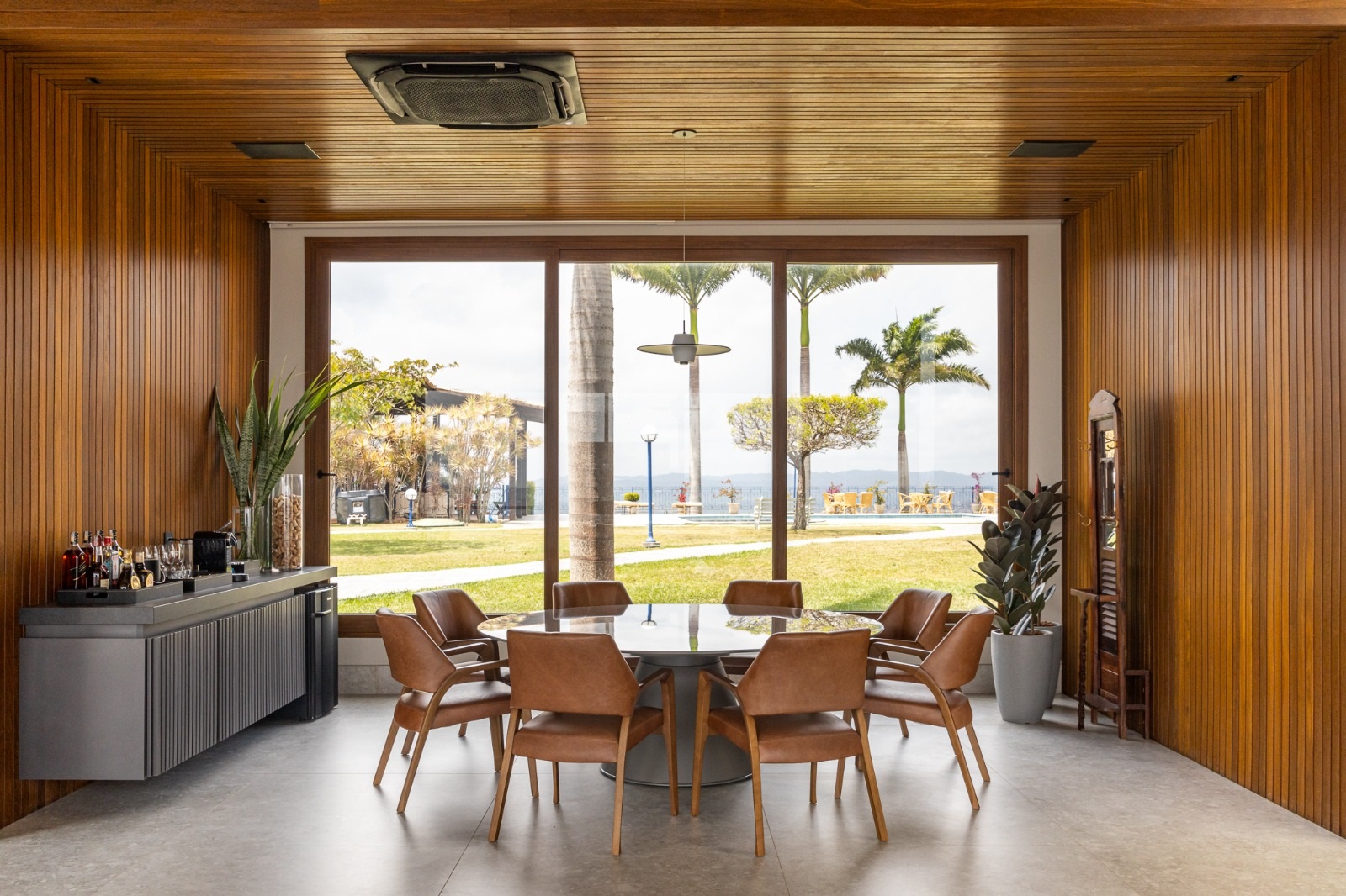 Sala de jantar com ampla porta de vidro. As paredes e o teto são revestidos com madeira