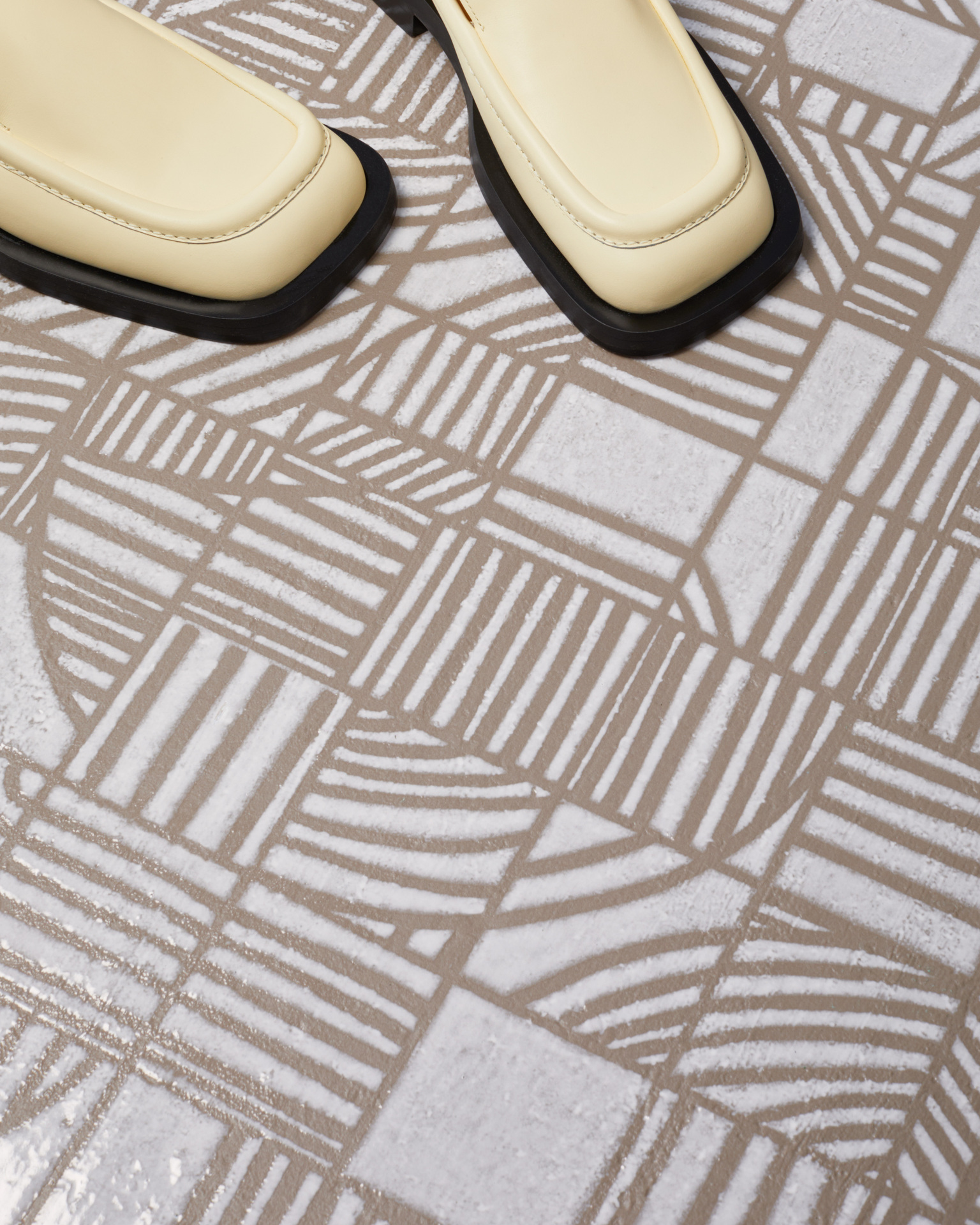 Piso com revestimento estampado em tom bege e branco, e pés com um sapato bege