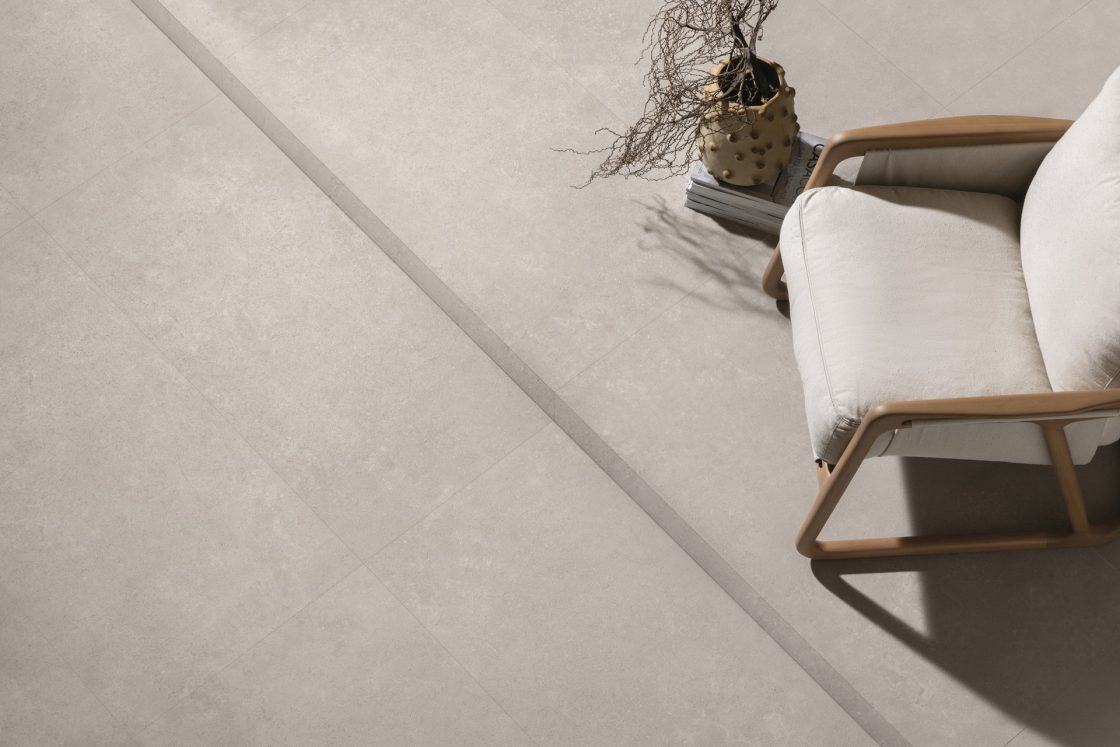 Visão de cima de piso com porcelanato em grande formato que reproduz pedra em tom de bege
