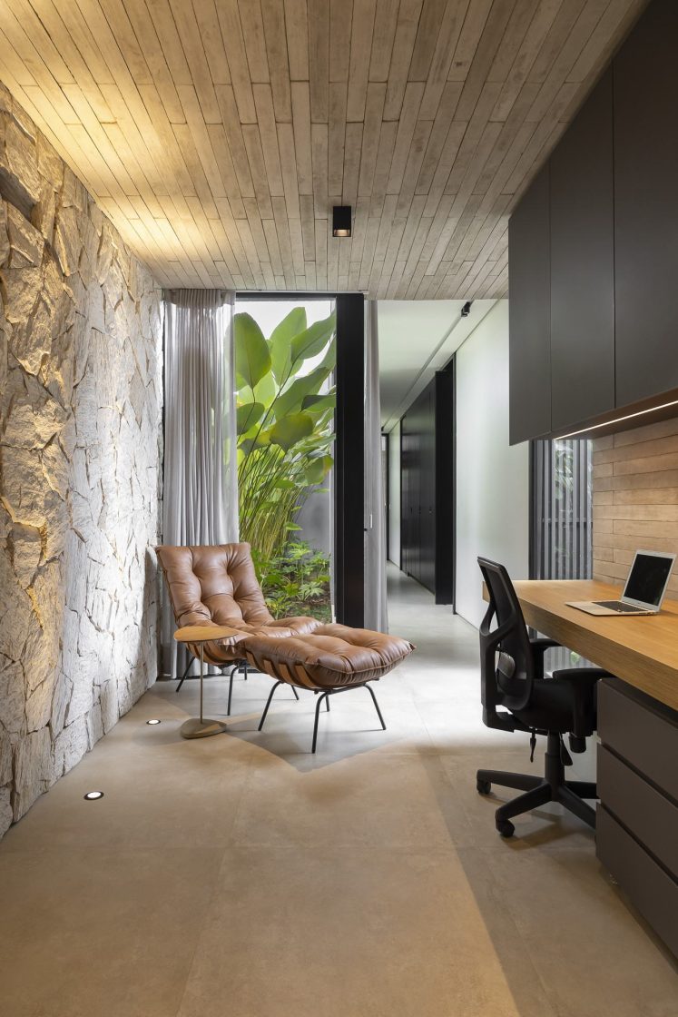 home office moderna com parede de pedra e cadeira chaise
