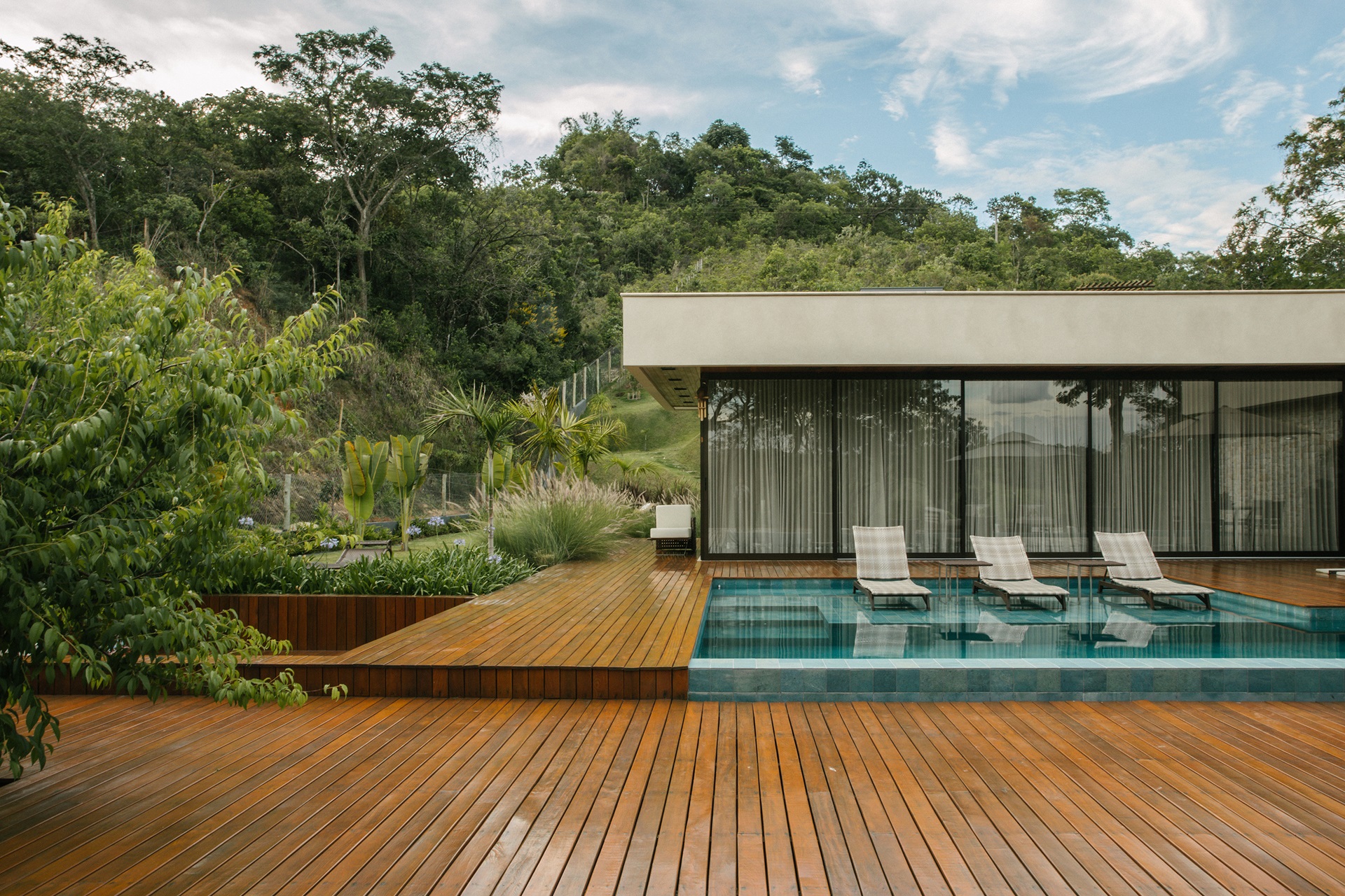 Piscina com prainha em área externa de casa em estilo moderno