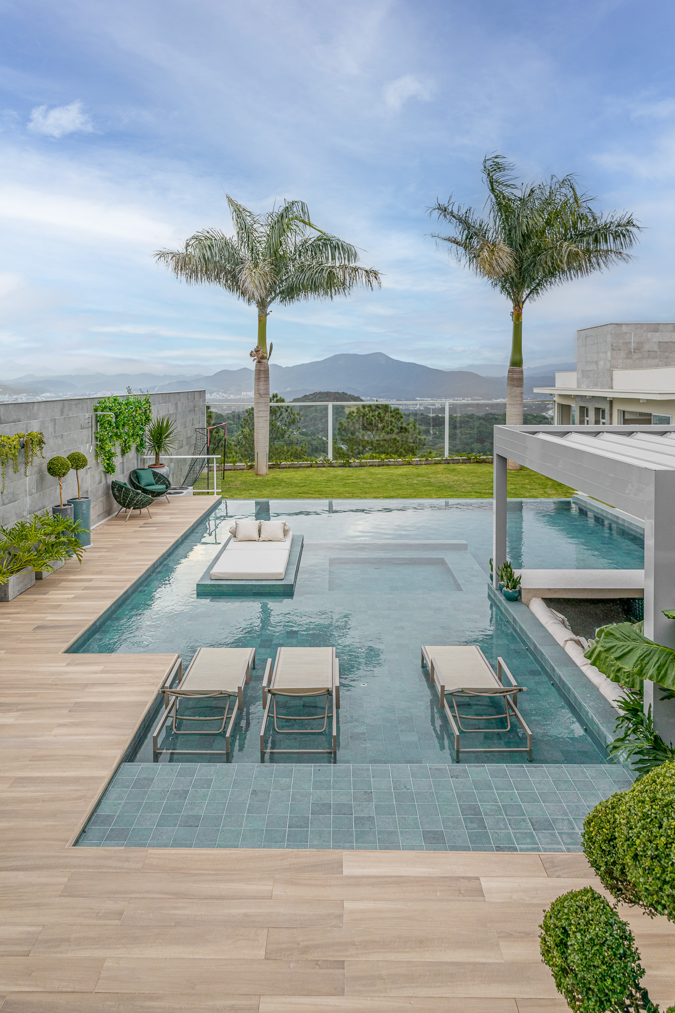 Piscina com revestimento azul e deck molhado em área com piso externo amadeirado