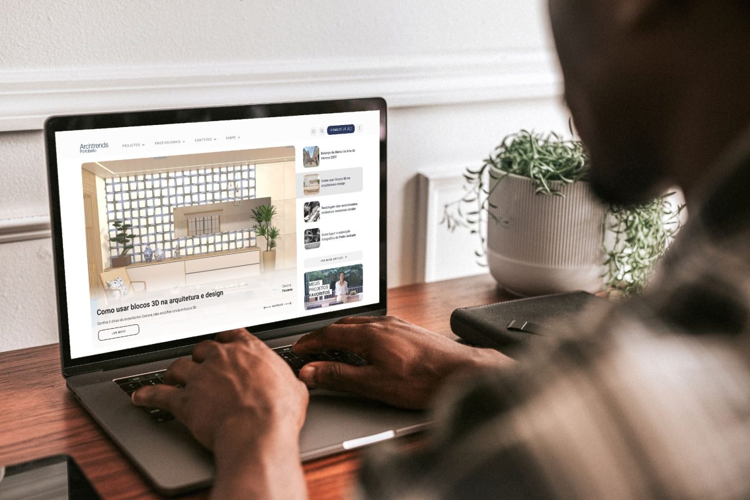 Pessoa navegando pelo portal Archtrends em um laptop. O rosto dela não aparece