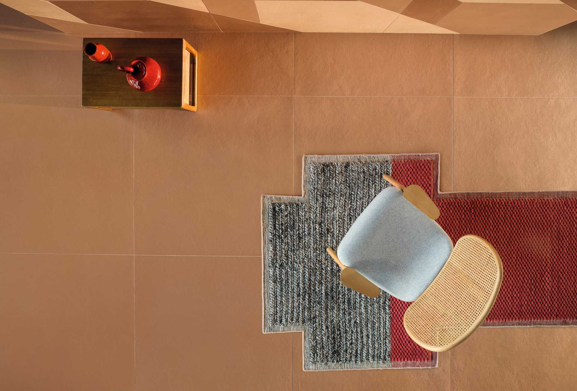 Sala vista de cima. Destaque para o piso terracota, uma cadeira e um tapete
