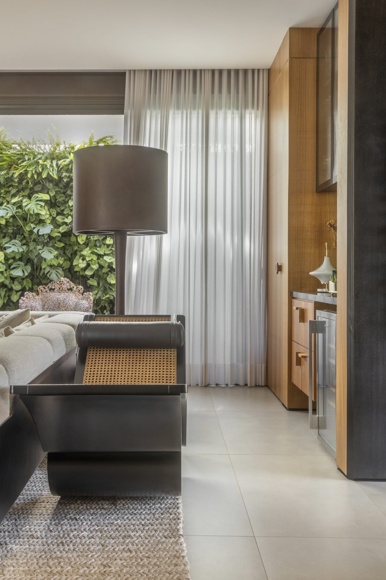 Quarto de casal com foco em uma cadeira projetada por Oscar Niemeyer. Acima dela há uma luminária pendente