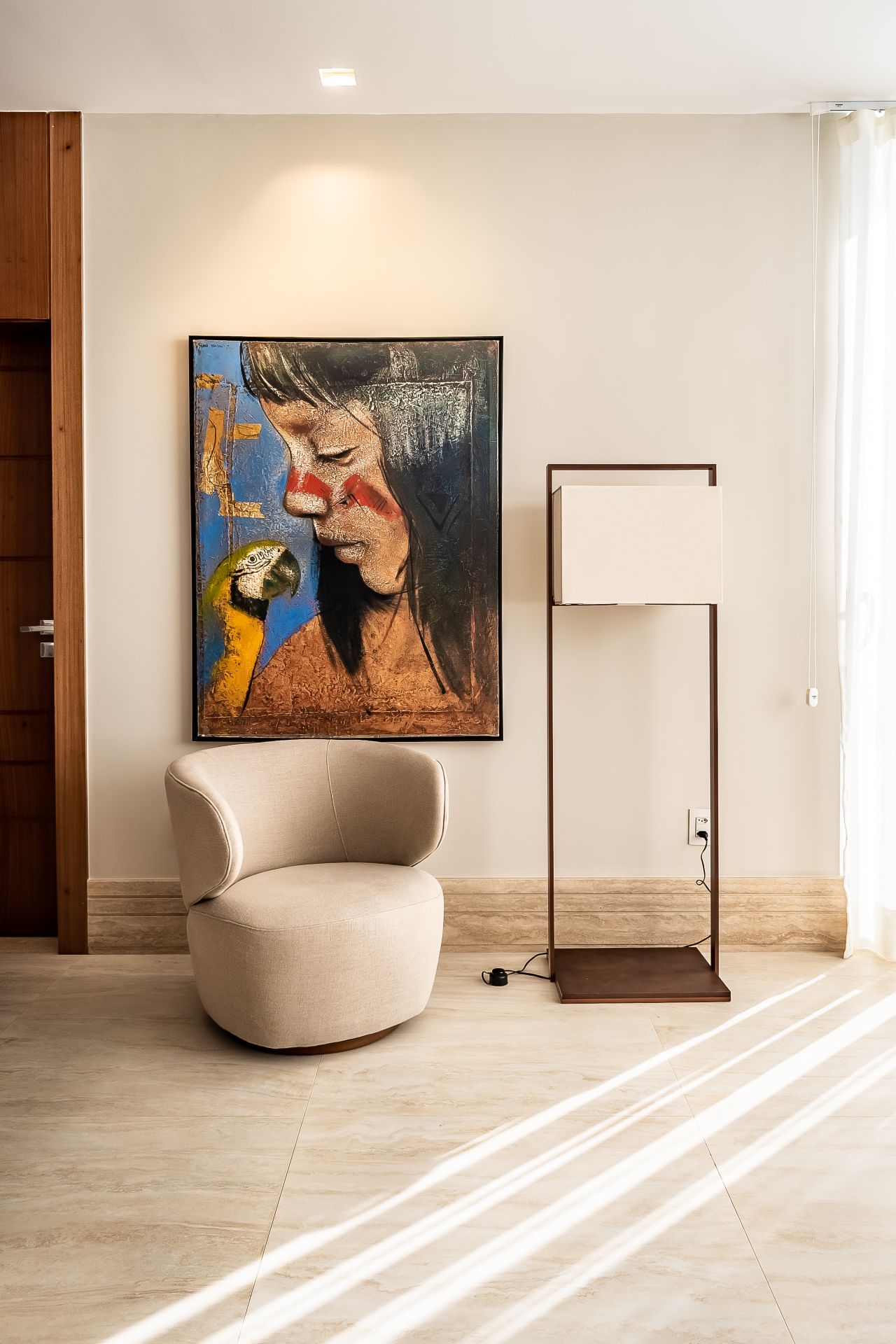 Detalhes de ambiente com poltrona, luminária e um quadro na parede
