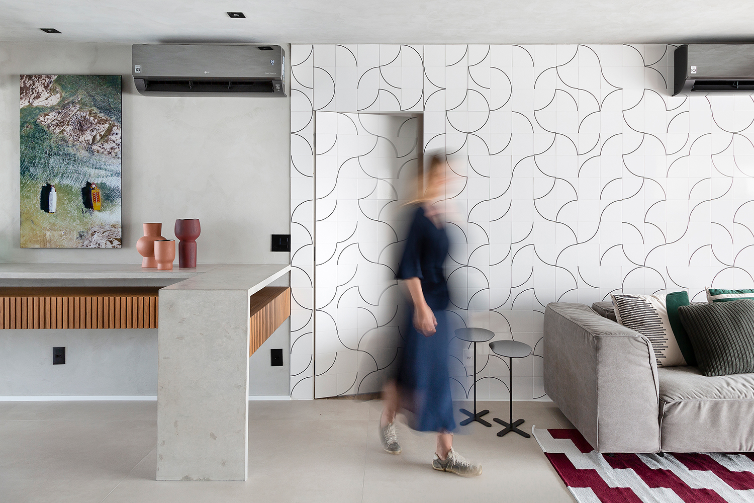 Sala com cozinha integrada e parede com azulejo branco com linhas pretas ao fundo