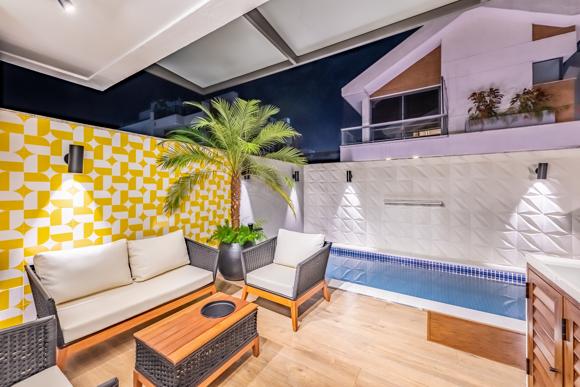 Área externa com piscina em alvenaria e parede em azulejo branco e amarelo
