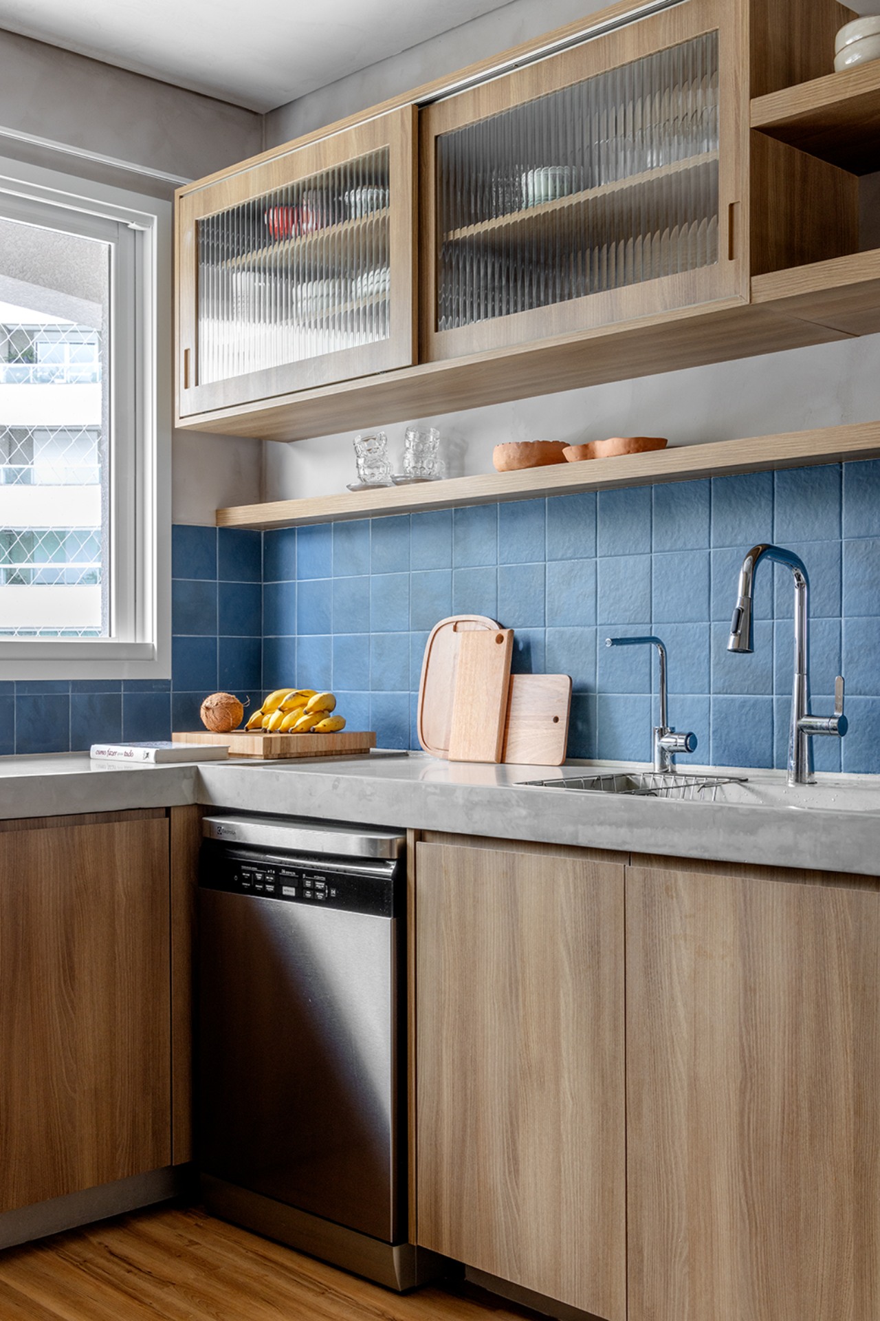 Cozinha com armários amadeirados e revestimento azul no backsplash