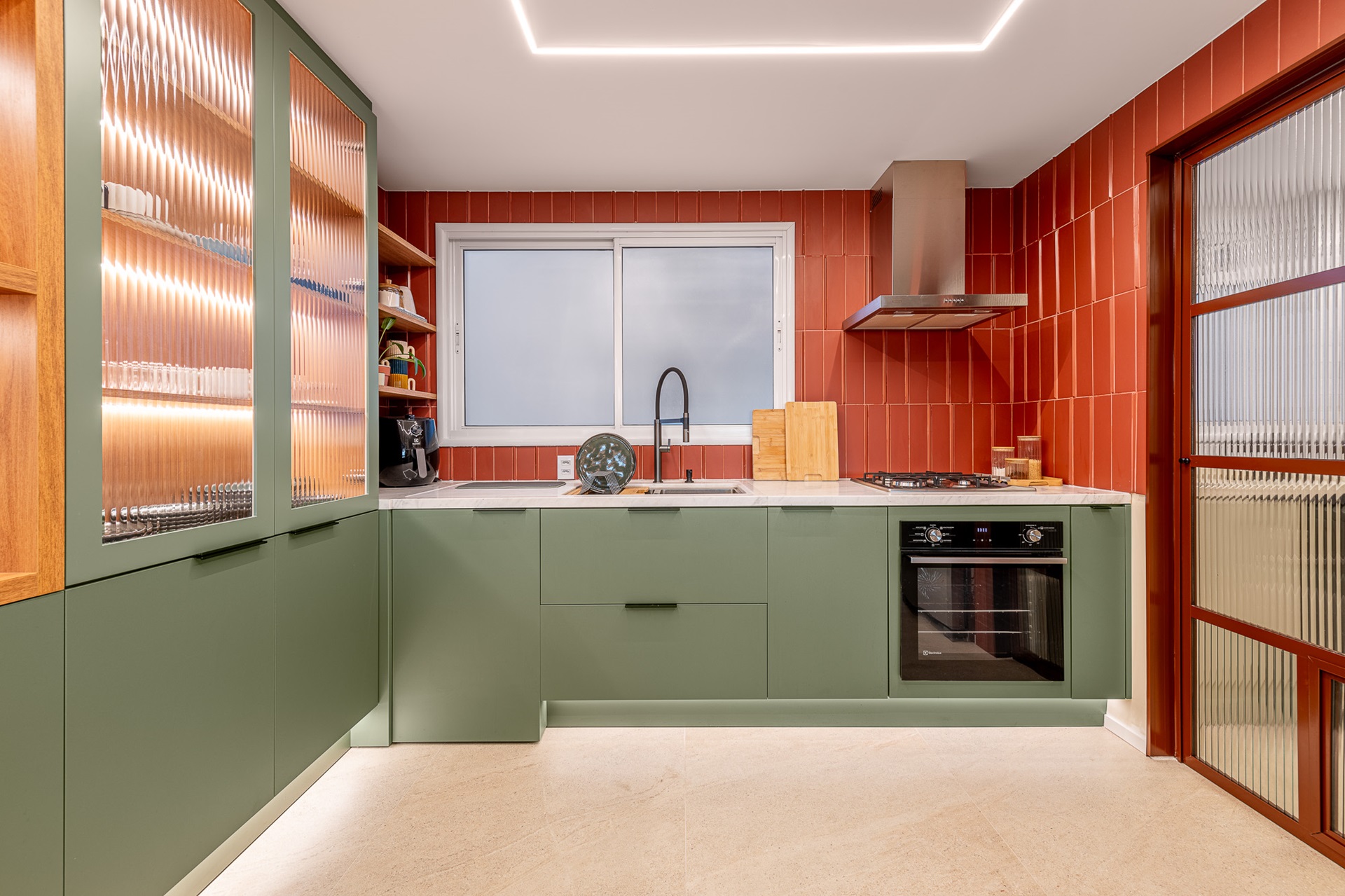 Cozinha com marcenaria verde e parede com revestimento terracota