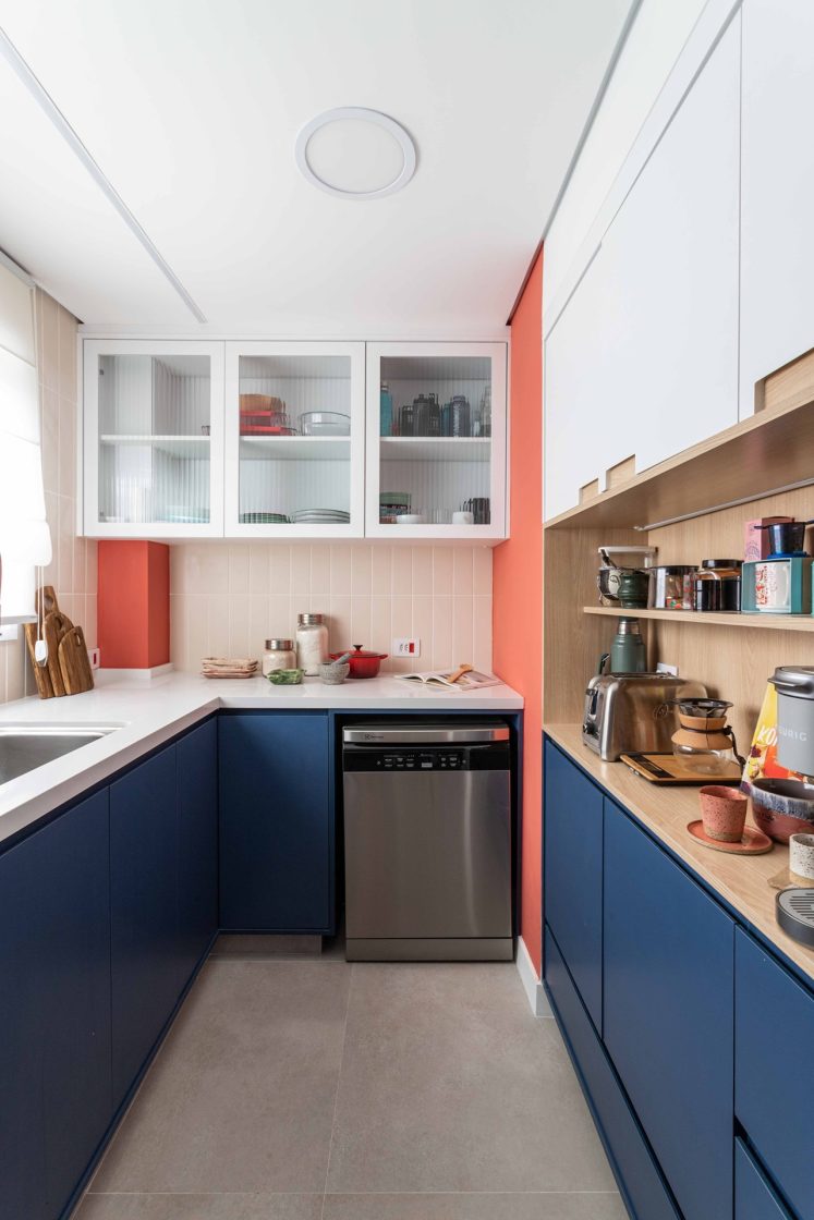 Cozinha em "U", com móveis em azul-escuro e paredes rosadas