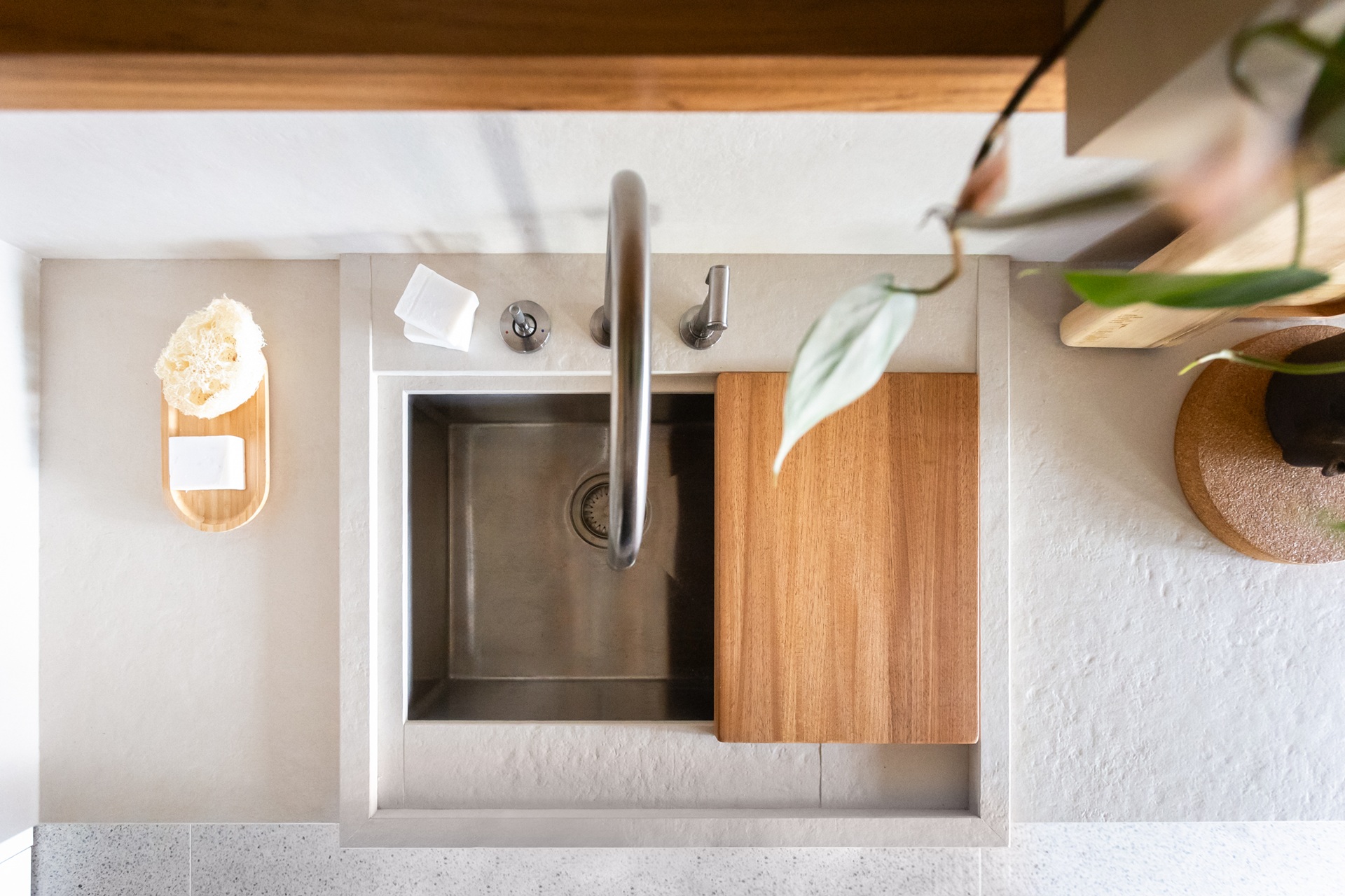 Pia farm sink vista do alto, com bancada ao lado em porcelanato e tábua de corte acoplada à cuba