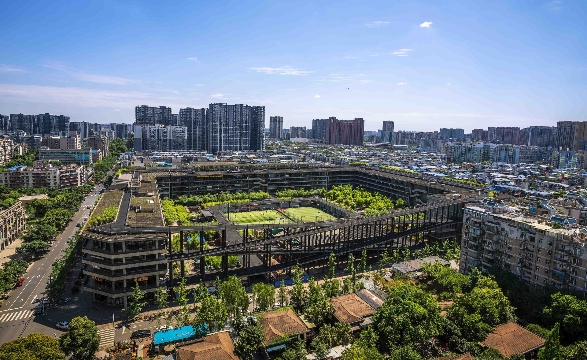 West Village, um grande complexo arquitetônico de formato retangular, com um espaço aberto no centro, repleto de vegetação e quadras esportivas
