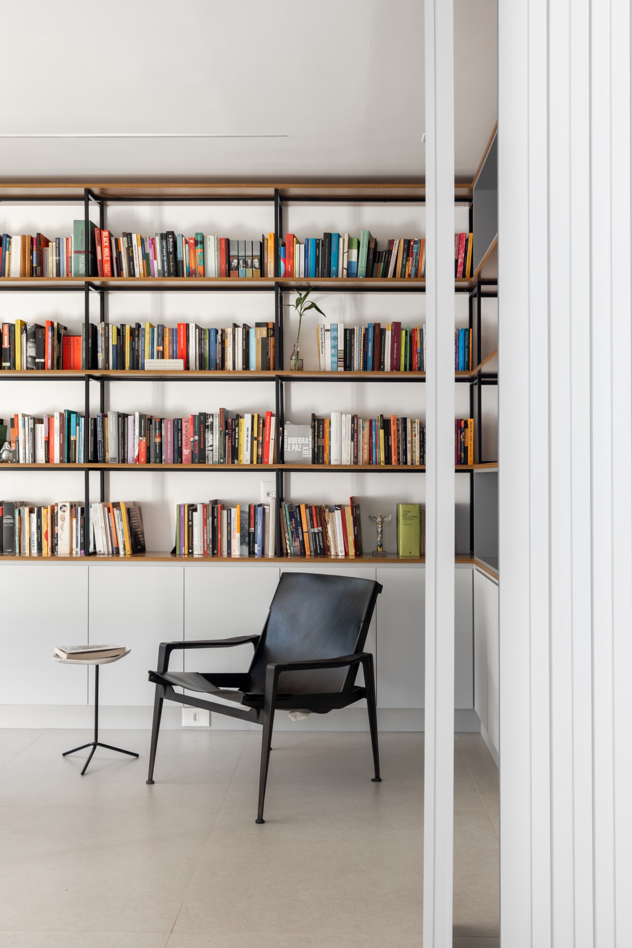 Sala de leitura com cadeira, mesinha e estante de livros